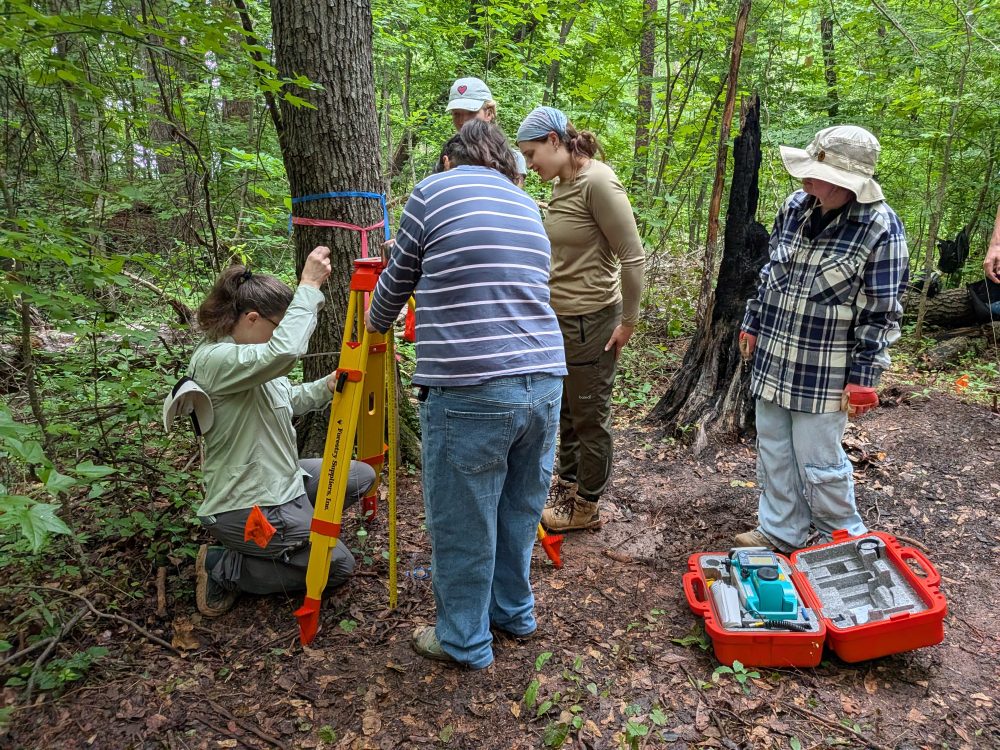 Several students adjusting a tool for archaeological site identification and records